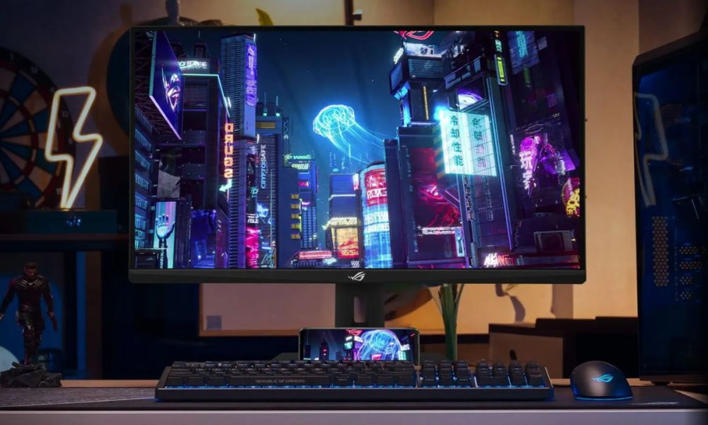 Monitor da gaming ASUS ROG Strix XG27ACMS da 27 pollici con risoluzione QHD e refresh rate a 320 Hz, mostrato su una scrivania da gamer con tastiera e mouse RGB mentre visualizza una scena cyberpunk ad alta definizione.