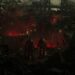 Requisitos Gears of War E-Day PC – escena oscura con dos soldados armados observando una ciudad en ruinas y en llamas durante la invasión en un entorno urbano devastado.