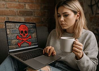 Protección de Red Windows - Mujer preocupada mirando su portátil con símbolo de calavera roja por virus informático, ilustrando la importancia de activar la protección de red en Windows para evitar hackers y malware.