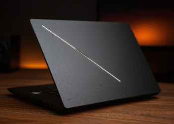 Asus ROG Zephyrus G16 2025 ¿Rey híbrido de juego y trabajo? - Alt text: "Asus ROG Zephyrus G16 2025 sleek black gaming laptop partially open on wooden desk with glowing diagonal light strip on lid, designed for hybrid gaming and work performance."