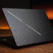 Asus ROG Zephyrus G16 2025 ¿Rey híbrido de juego y trabajo? - Alt text: "Asus ROG Zephyrus G16 2025 sleek black gaming laptop partially open on wooden desk with glowing diagonal light strip on lid, designed for hybrid gaming and work performance."