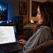 Privacidad en Windows 11 - Mujer usando un portátil en casa configurando opciones de privacidad en Windows 11 con O&O ShutUp10++, mostrando ajustes de seguridad y control de datos en pantalla.