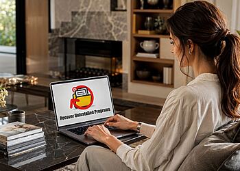 Programas desinstalados Windows 11 - Mujer usando un portátil para recuperar programas desinstalados en Windows 11.