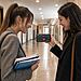 Volumen de Android - Dos estudiantes consultan en un teléfono Android una aplicación para ajustar el volumen según un horario en el pasillo de una facultad de Derecho.